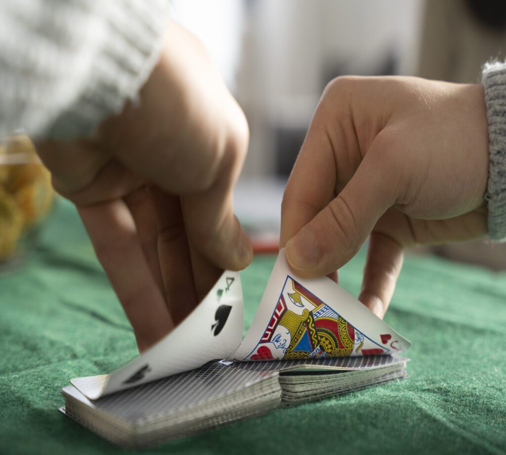 Close-up of hands in a gambling bust dealing cards on green felt.