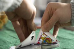 Close-up of hands in a gambling bust dealing cards on green felt.