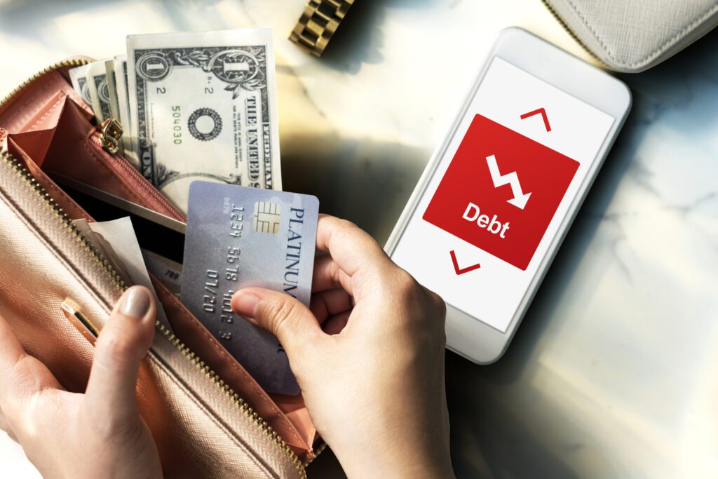 Hand holding a card with a phone showing debt reduction for credit management.